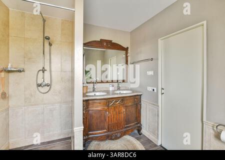 A beautifully designed modern bathroom featuring wood elements, dual sinks, and a spacious shower area, creating a serene and functional space. Stock Photo