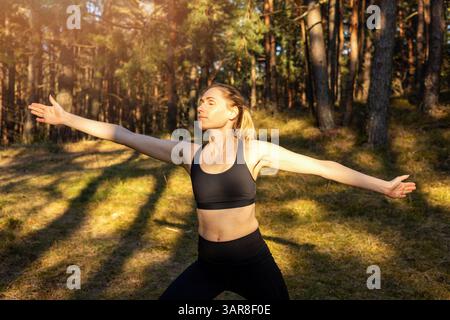 woman doing pilates workout in a sunny forest. enjoying the beauty of mindfulness and nature Stock Photo