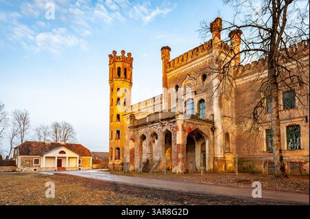 The Odziena Manor, a castle built in the neo-Gothic style, destroyed, against the blue sky. Landscape in early spring. Stock Photo
