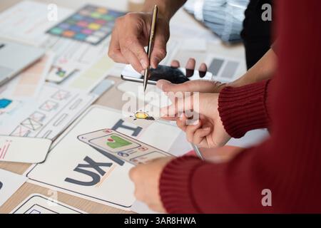 Collaboration and UX Design. Team members discussing and brainstorming UX ideas using design prototypes. Stock Photo