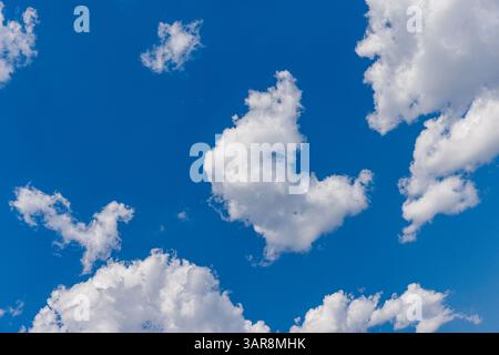 Sunny day with a clear blue sky and soft white clouds, perfect for peaceful nature scenes, outdoor backgrounds, and bright summer weather inspiration Stock Photo