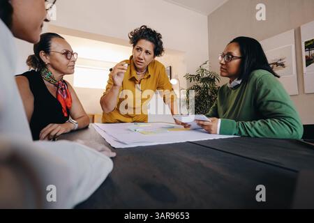 A team gathers around a table to discuss project strategies, fostering collaboration and decision-making in a professional work environment. Stock Photo