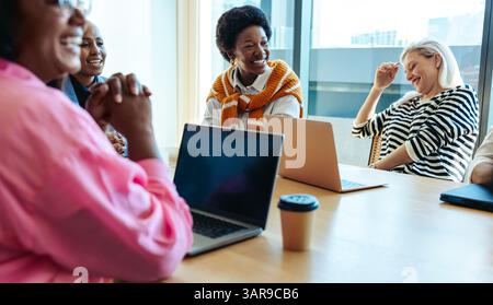 A dynamic female team collaborates during a marketing meeting, fostering teamwork and professional interaction in a modern office environment. Stock Photo