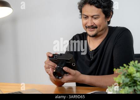 A young male photographer working from home, editing photos on his laptop Stock Photo