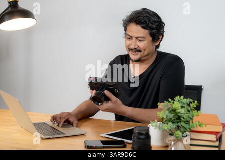 A young male photographer working from home, editing photos on his laptop Stock Photo