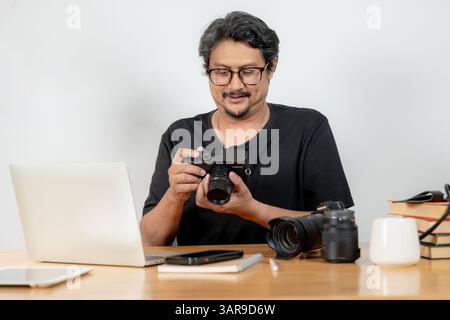A young male photographer working from home, editing photos on his laptop Stock Photo