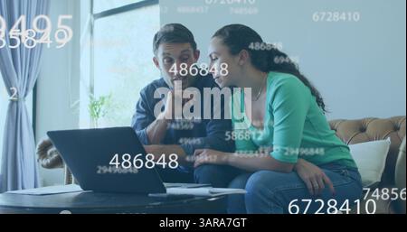 Multiple changing numbers floating over caucasian couple calculating finance together at home Stock Photo