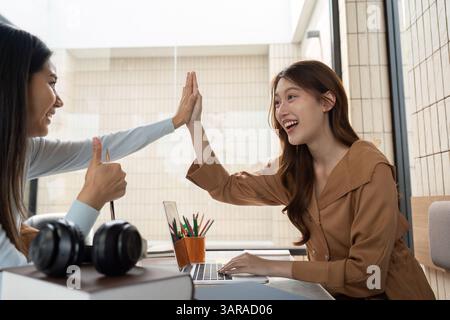 Joyful Learning and Collaboration. Two students share a high five, celebrating a successful study moment. Stock Photo