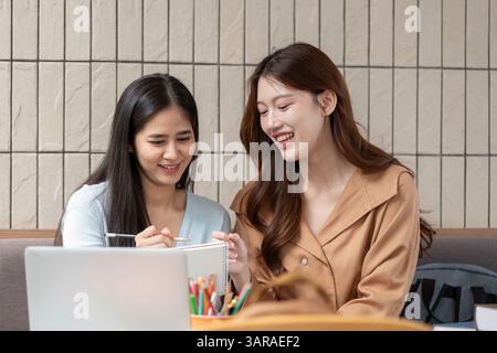 Collaboration and Engagement. Two students laughing together while reviewing their notes and study materials. Stock Photo