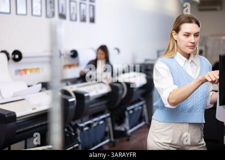 Technician operator calibrating plotter machine, typing on computer keyboard Stock Photo
