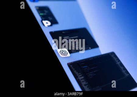 Poznan, Poland – April 14, 2025: Close-up of a tilted monitor with ChatGPT icon and code editors, showing integration of AI tools in modern digital de Stock Photo
