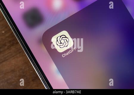 Poznan, Poland – April 14, 2025: Close-up of ChatGPT mobile icon on smartphone resting on a wooden table, highlighting mobile AI access in a natural d Stock Photo
