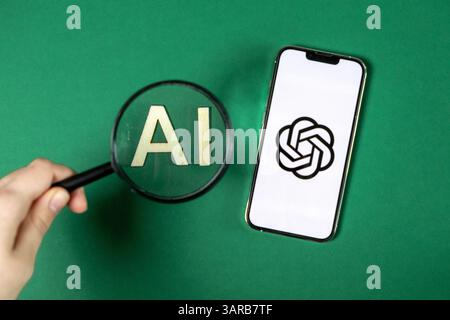 Poznan, Poland – April 14, 2025: Close-up of hand holding magnifier over AI letters beside smartphone showing ChatGPT logo, representing search and fo Stock Photo