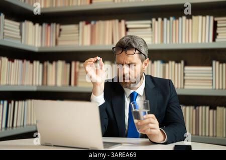 Medicine pill from headache migraine. Tired, headache and eye strain on laptop. Man with stress, burnout and fatigue eyestrain. Business man rubbing Stock Photo