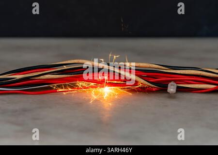 there is a fire burning in the electric wires, sparks fly on a dark background. A short circuit in the electrical wiring, the cause of the fire. Flame Stock Photo