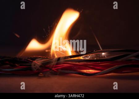 The twisted electrical wiring is smoking, burning and sparking on a dark background. Short circuit in the wires. Flames, sparks and smoke Stock Photo