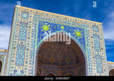 Vibrant Islamic building showcasing stunning tilework and intricate designs. Tilya-Kori Madrasah entrance portal on a sunny day. Registan square, Sama Stock Photo