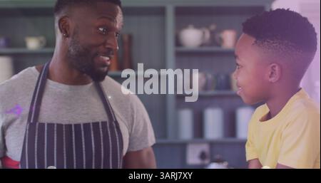 Image of lights over happy african american father and son cooking together Stock Photo