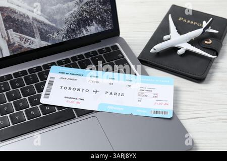 Flight ticket, passport, plane model and laptop on white wooden table, closeup Stock Photo