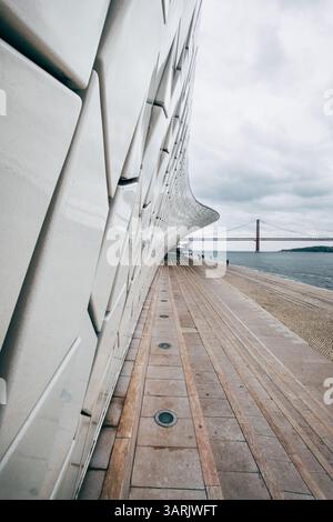 The curved walls of the MAAT Museum stand as architectural masterpiece, showcasing the beauty of modern design and construction. The 25 de Abril Bridg Stock Photo