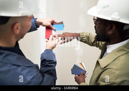 Over shoulder view of two biracial interior designers discussing color palette while working at construction site Stock Photo