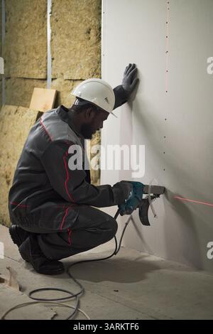Vertical shot of African American worker using red laser level while working at construction site Stock Photo