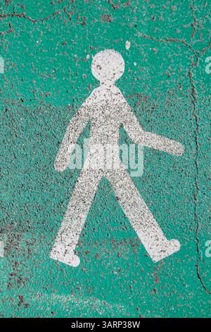 rotten pedestrian walking sign in white on green background in France at the floor Stock Photo