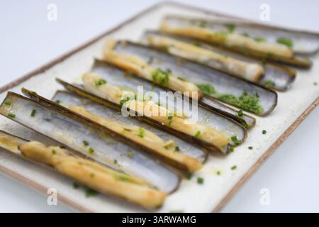 Platter of razor clams with garlic and parsley Stock Photo
