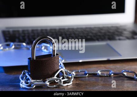 Padlock with chain and laptop on table, closeup. Cyber security concept Stock Photo