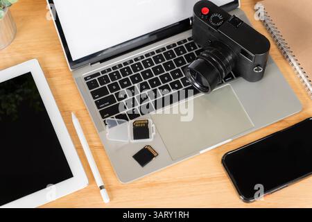 Top view. Flat lay. Laptop, external hard drive, modern digital camera. Two sd memory cards and lens on gray background. Photographer's equipment, sma Stock Photo