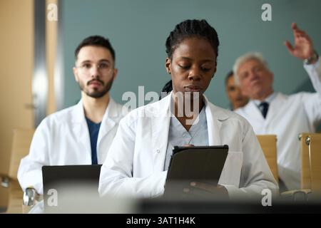 Portrait of diverse medical team collaborating during an important meeting Reviewing patient data on digital tablets and discussing medical cases Stock Photo