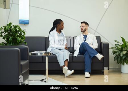 Medical Professionals Discussing Work on a Couch in Clinic Stock Photo