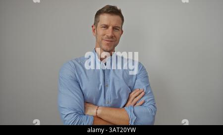 Young man with arms crossed smiling confidently against an isolated white background, showcasing his handsome and attractive appearance in this portra Stock Photo