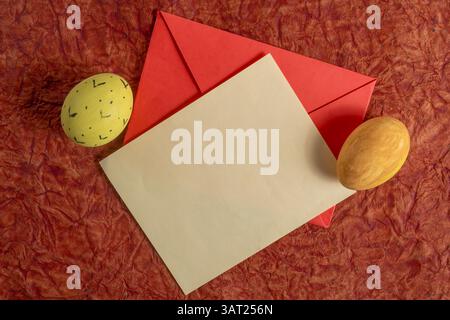A colorful Easter composition with a red envelope, decorated eggs, and brown cardboard box, perfect for holiday promotions or art projects. Stock Photo