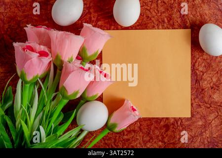 Soft pink roses, white eggs and orange background, perfect for spring, seasonal greeting cards, festive advertising design. Stock Photo