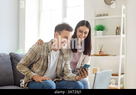 Married Couple Enjoying Online Entertainment Using A Smartphone At Home Stock Photo