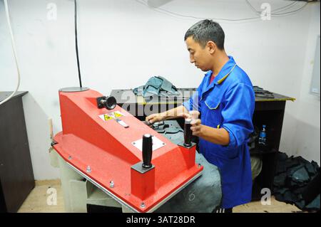 A worker repairs an embroidery machine in a sewing workshop Stock Photo