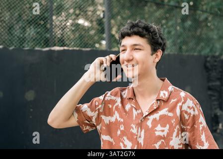 Smiling young man talking on phone outdoors Stock Photo