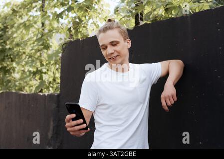 Smiling young man using smartphone outdoors Stock Photo