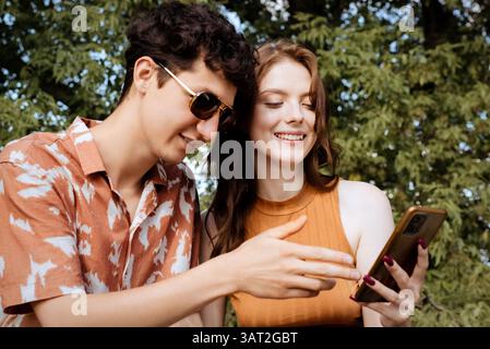 Young couple happily discussing content on smartphone Stock Photo