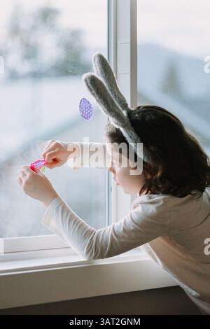 Child decorating window with Easter stickers and eggs. Stock Photo