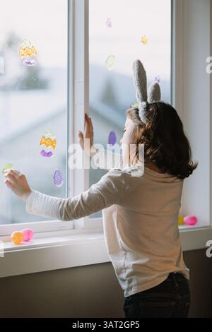 Child decorating window with Easter stickers and eggs. Stock Photo