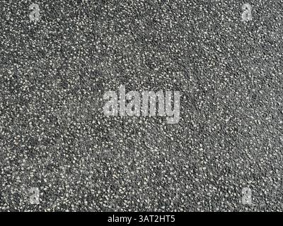 Asphalt road surface with white gravel ensures grip and safety. Interesting texture, ideal as a background or for road construction themes. Stock Photo