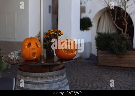 Two carved pumpkins on a barrel table in a festive outdoor setting Stock Photo