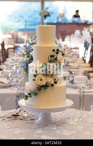 Four-tier white wedding cake with floral dÃ©cor on reception tab Stock Photo