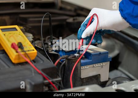 Electrical engineer uses multimeter to test electrical installation and motor current of a car in an auto workshop Stock Photo