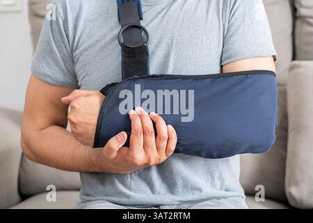Close up portrait of a disabled man grabbing his painful bandaged arm on a couch at home Stock Photo