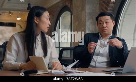 Two business colleagues coworkers Asian woman Korean businesswoman female girl Chinese man Japanese businessman guy male at office boring lazy playing Stock Photo