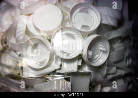 A close-up view of a collection of white bottle caps in a plastic container, plastic parts. White bottle caps, revealing details of the plastic. Stock Photo