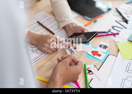 Creative Collaboration and Mobile Design. Hands-on teamwork focusing on smartphone app designs with logos and UI sketches. Stock Photo